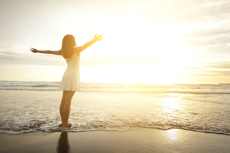 Mujer con vestido blanco en la playa al atardecer